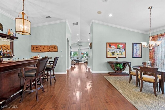 dining area featuring lofted ceiling, ceiling fan with notable chandelier, dark hardwood / wood-style floors, and crown molding