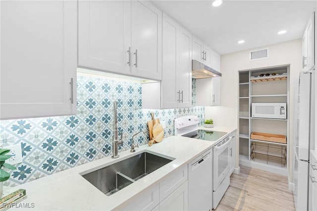 kitchen with decorative backsplash, light wood-type flooring, white appliances, sink, and white cabinets