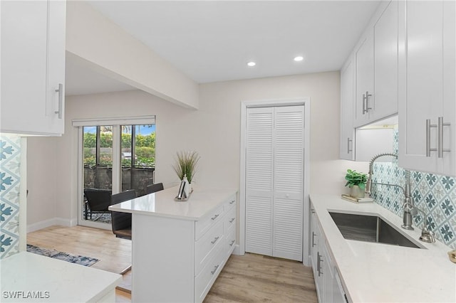 kitchen with white cabinets, light hardwood / wood-style floors, sink, and tasteful backsplash