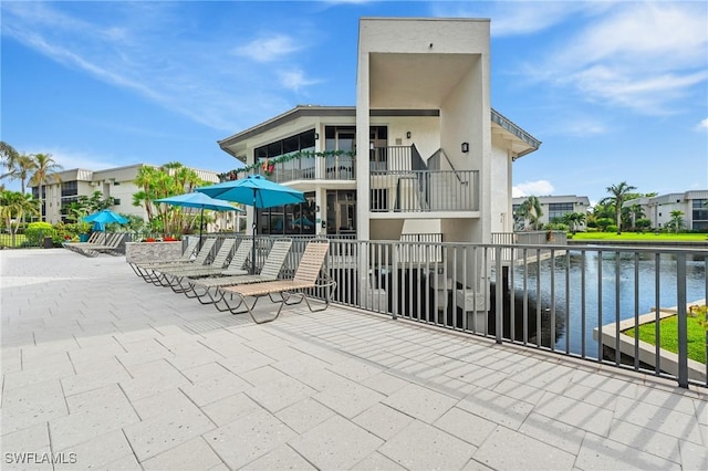 view of patio featuring a water view and a balcony