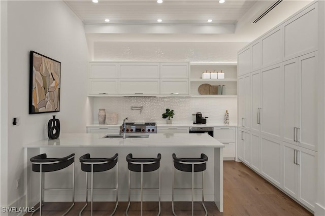 kitchen with white cabinetry, a kitchen breakfast bar, a sink, and light countertops