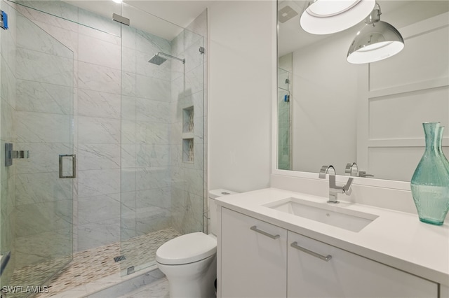 bathroom featuring a stall shower, marble finish floor, vanity, and toilet