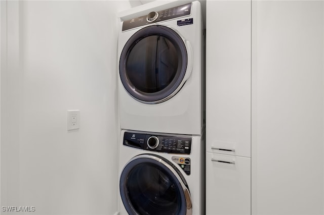 clothes washing area featuring cabinet space and stacked washer / dryer