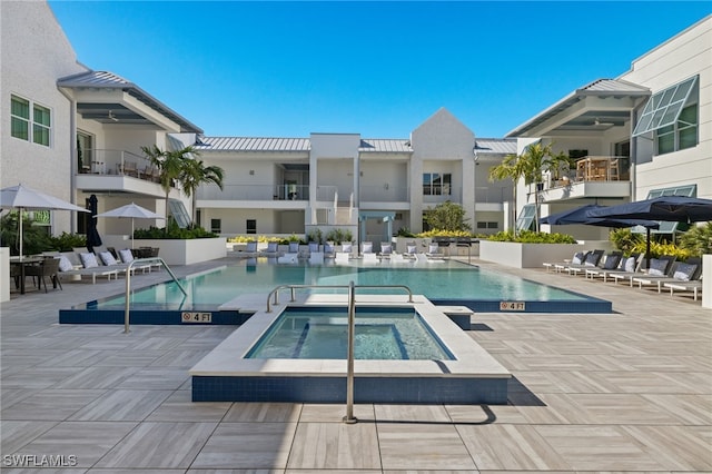 community pool with a patio area and a hot tub