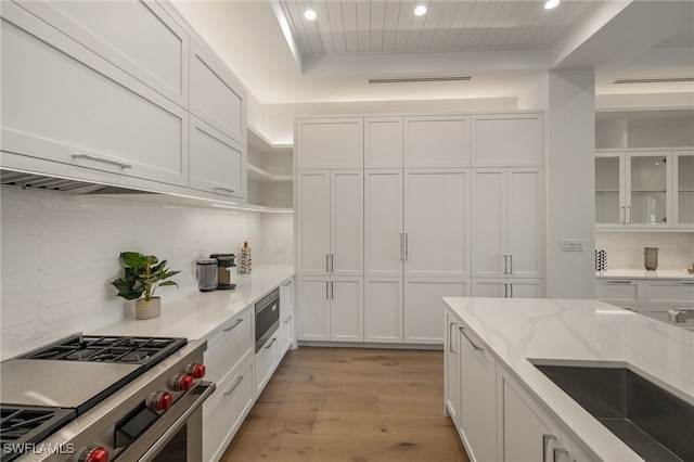 kitchen with appliances with stainless steel finishes, white cabinetry, and glass insert cabinets