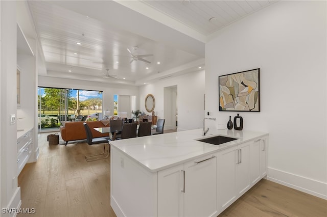 kitchen with recessed lighting, light wood-style flooring, open floor plan, white cabinetry, and a sink