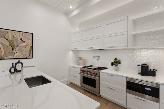 kitchen featuring tasteful backsplash, stainless steel appliances, white cabinetry, open shelves, and a sink