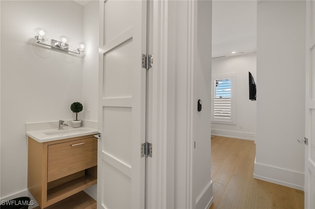 bathroom with wood finished floors, vanity, and baseboards