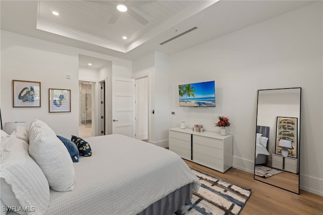 bedroom with baseboards, a raised ceiling, a ceiling fan, light wood-style flooring, and recessed lighting