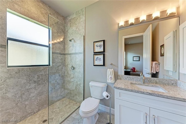 bathroom with tiled shower, vanity, and toilet