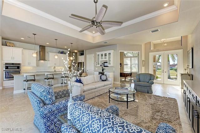 living room with french doors, sink, ornamental molding, a raised ceiling, and ceiling fan