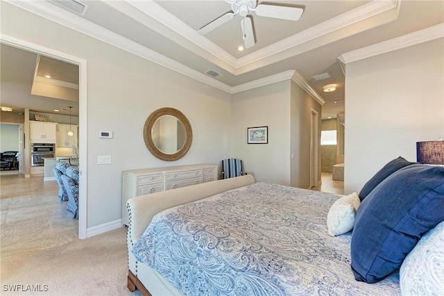 carpeted bedroom with a tray ceiling, ornamental molding, ceiling fan, and ensuite bathroom