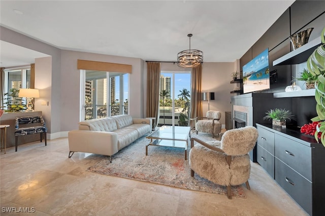 living area featuring a fireplace, baseboards, and a notable chandelier