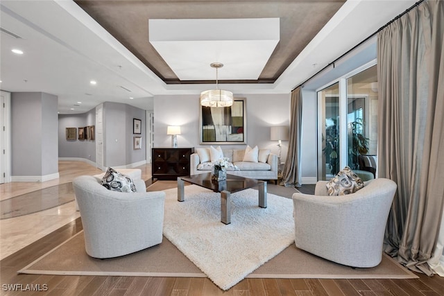 living room with baseboards, a raised ceiling, wood finished floors, and recessed lighting