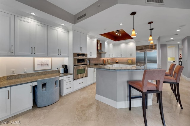 kitchen with appliances with stainless steel finishes, wall chimney range hood, white cabinetry, and recessed lighting