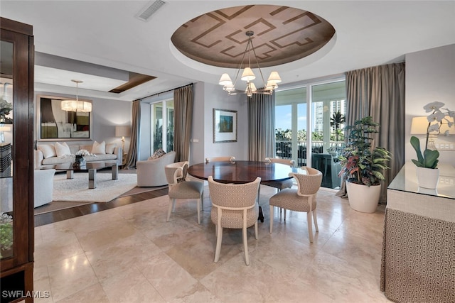 dining space with an inviting chandelier, visible vents, and a tray ceiling