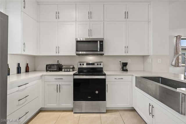 kitchen with white cabinetry, sink, light tile patterned floors, and stainless steel appliances