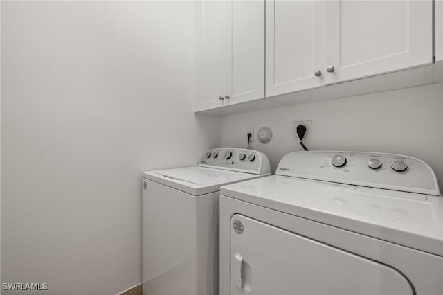 clothes washing area featuring cabinets and separate washer and dryer