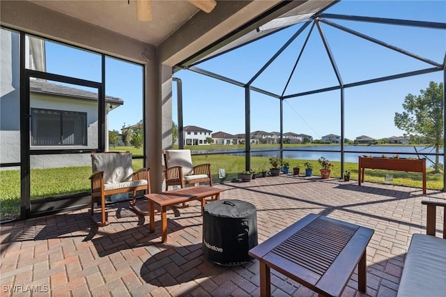 view of patio featuring a water view, ceiling fan, and a lanai