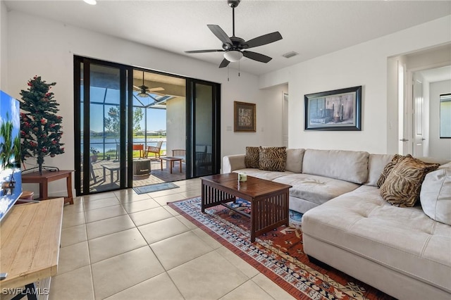 tiled living room featuring ceiling fan and a water view