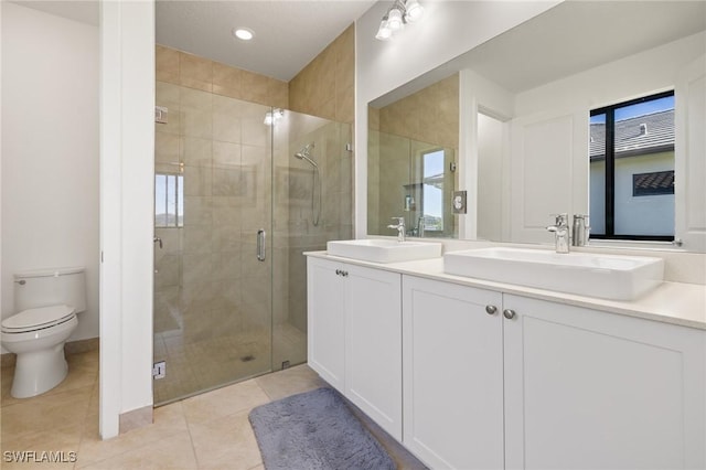 bathroom featuring tile patterned flooring, vanity, toilet, and a shower with door