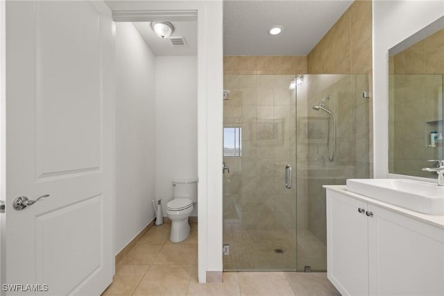 bathroom with tile patterned floors, vanity, a shower with shower door, and toilet