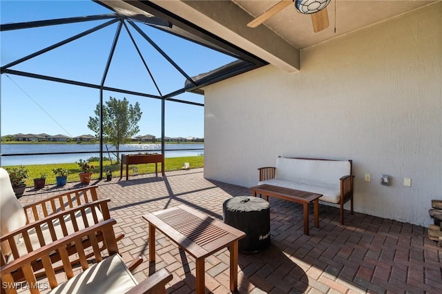 view of patio / terrace featuring a water view, glass enclosure, and ceiling fan