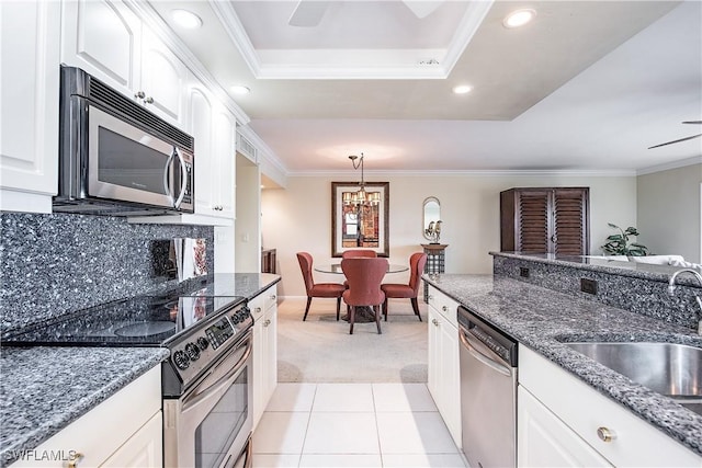 kitchen with white cabinets, sink, dark stone countertops, light colored carpet, and stainless steel appliances