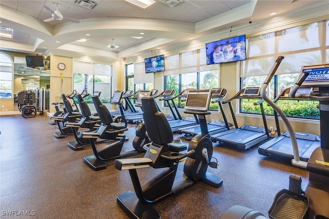 workout area featuring a tray ceiling and ornamental molding