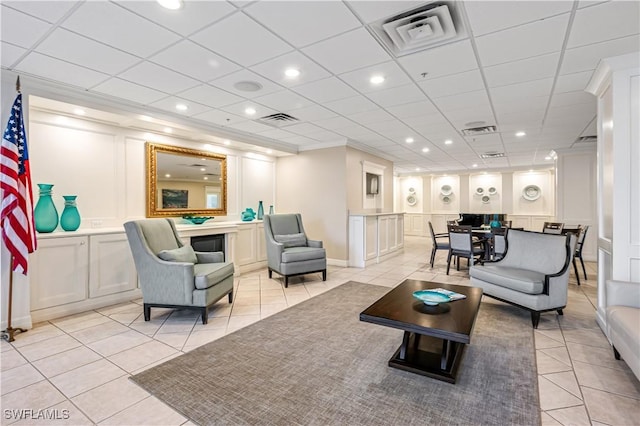 living room with visible vents, light tile patterned flooring, and a decorative wall