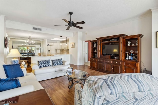 living room with ceiling fan with notable chandelier, dark hardwood / wood-style flooring, and crown molding