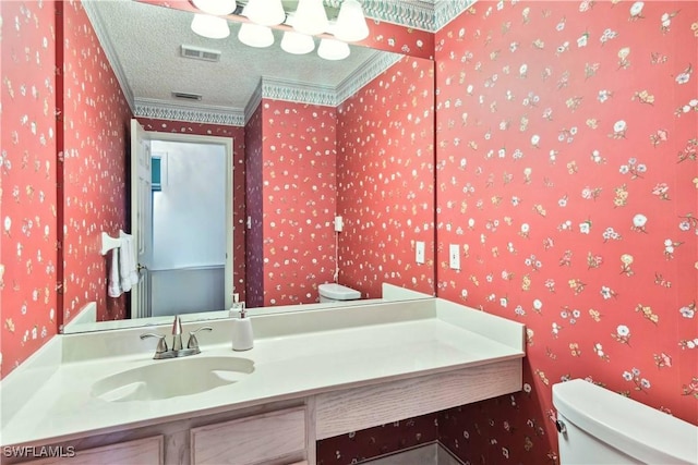 bathroom with vanity, toilet, ornamental molding, and a textured ceiling