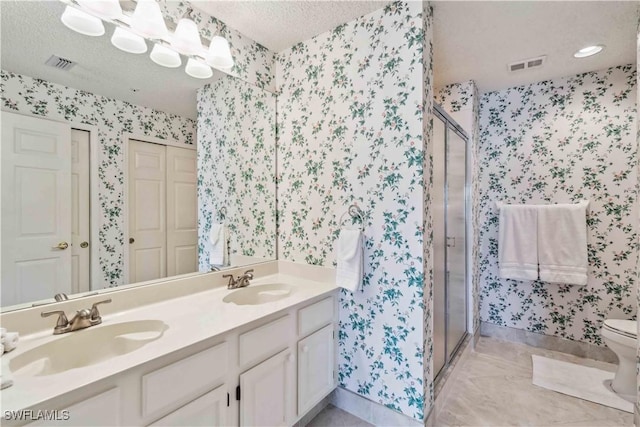 bathroom featuring vanity, toilet, an enclosed shower, and a textured ceiling