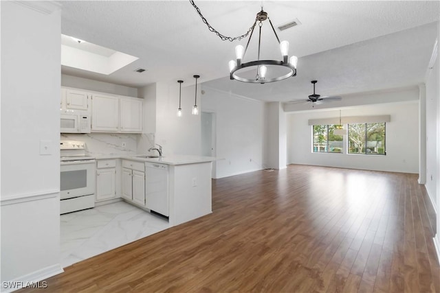 kitchen with white appliances, a peninsula, open floor plan, and light countertops