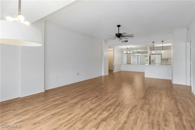 unfurnished living room with visible vents, ceiling fan with notable chandelier, and light wood-type flooring