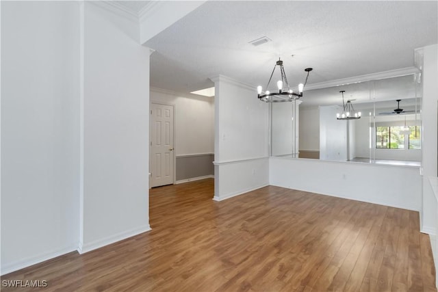 interior space featuring wood finished floors, baseboards, visible vents, ornamental molding, and ceiling fan with notable chandelier