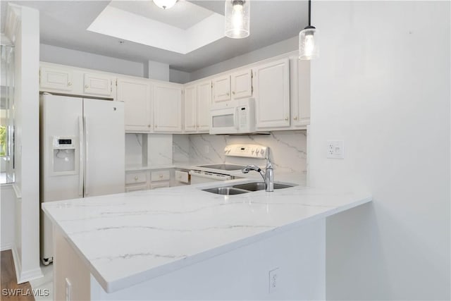 kitchen featuring white appliances, light stone counters, a peninsula, a sink, and decorative backsplash