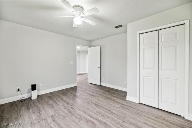 unfurnished bedroom featuring ceiling fan, a closet, and light wood-type flooring