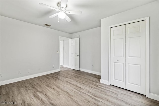 unfurnished bedroom featuring ceiling fan, a closet, and light wood-type flooring