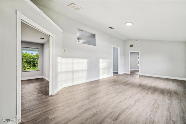 empty room with dark hardwood / wood-style flooring, vaulted ceiling, and ceiling fan