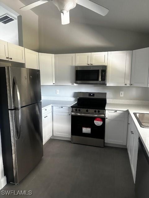 kitchen with ceiling fan, white cabinets, stainless steel appliances, and vaulted ceiling