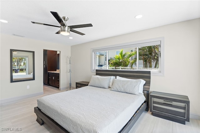 bedroom featuring ceiling fan, light wood-type flooring, and ensuite bath