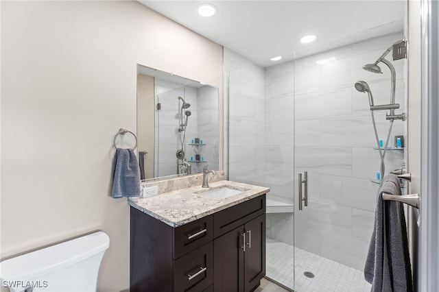 bathroom featuring tile patterned floors, vanity, a shower with shower door, and toilet