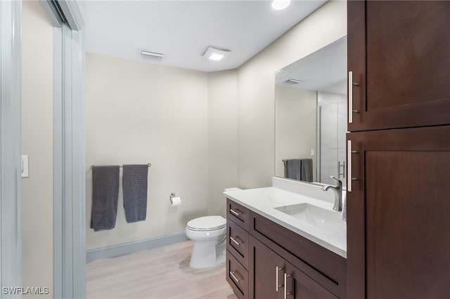 bathroom featuring wood-type flooring, vanity, toilet, and walk in shower