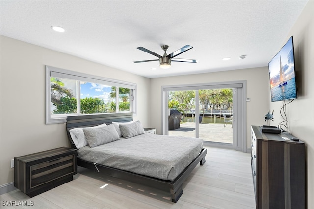 bedroom with access to exterior, ceiling fan, light hardwood / wood-style flooring, and a textured ceiling