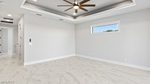 spare room with a tray ceiling and ceiling fan