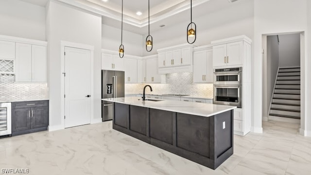 kitchen with appliances with stainless steel finishes, a kitchen island with sink, sink, pendant lighting, and white cabinets