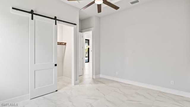 unfurnished bedroom with ceiling fan and a barn door