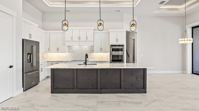 kitchen with a tray ceiling, white cabinetry, stainless steel appliances, and decorative light fixtures