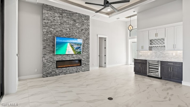 kitchen featuring white cabinetry, beverage cooler, a high ceiling, decorative light fixtures, and a fireplace